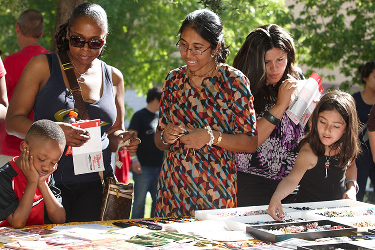 A group of people looking at a craft table.