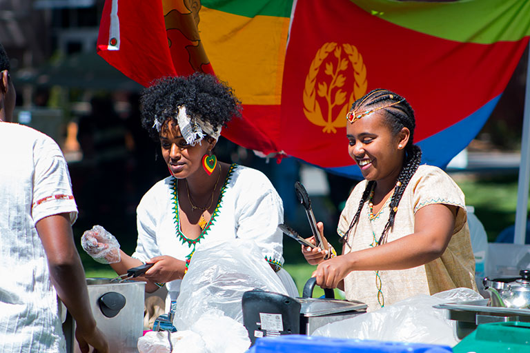 Two women serving food to festival attendees.
