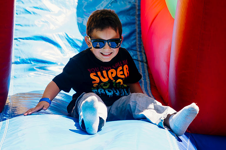 Young boy sliding down a bounce-house slide.