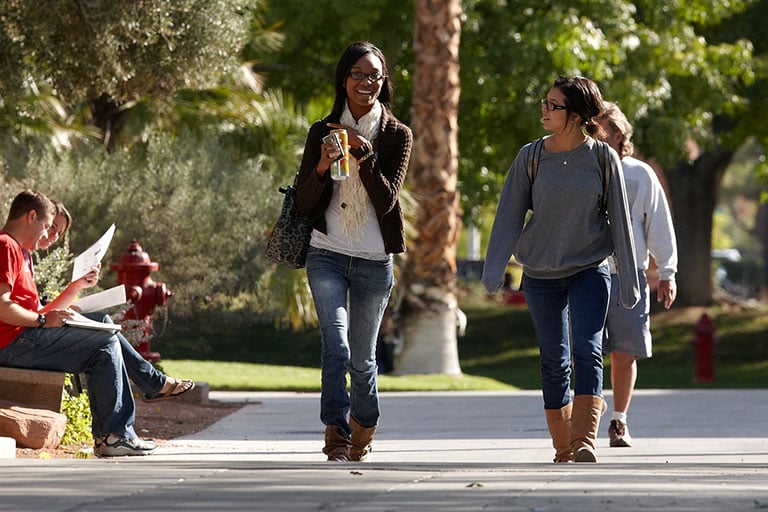 Two female students walking outside on campus